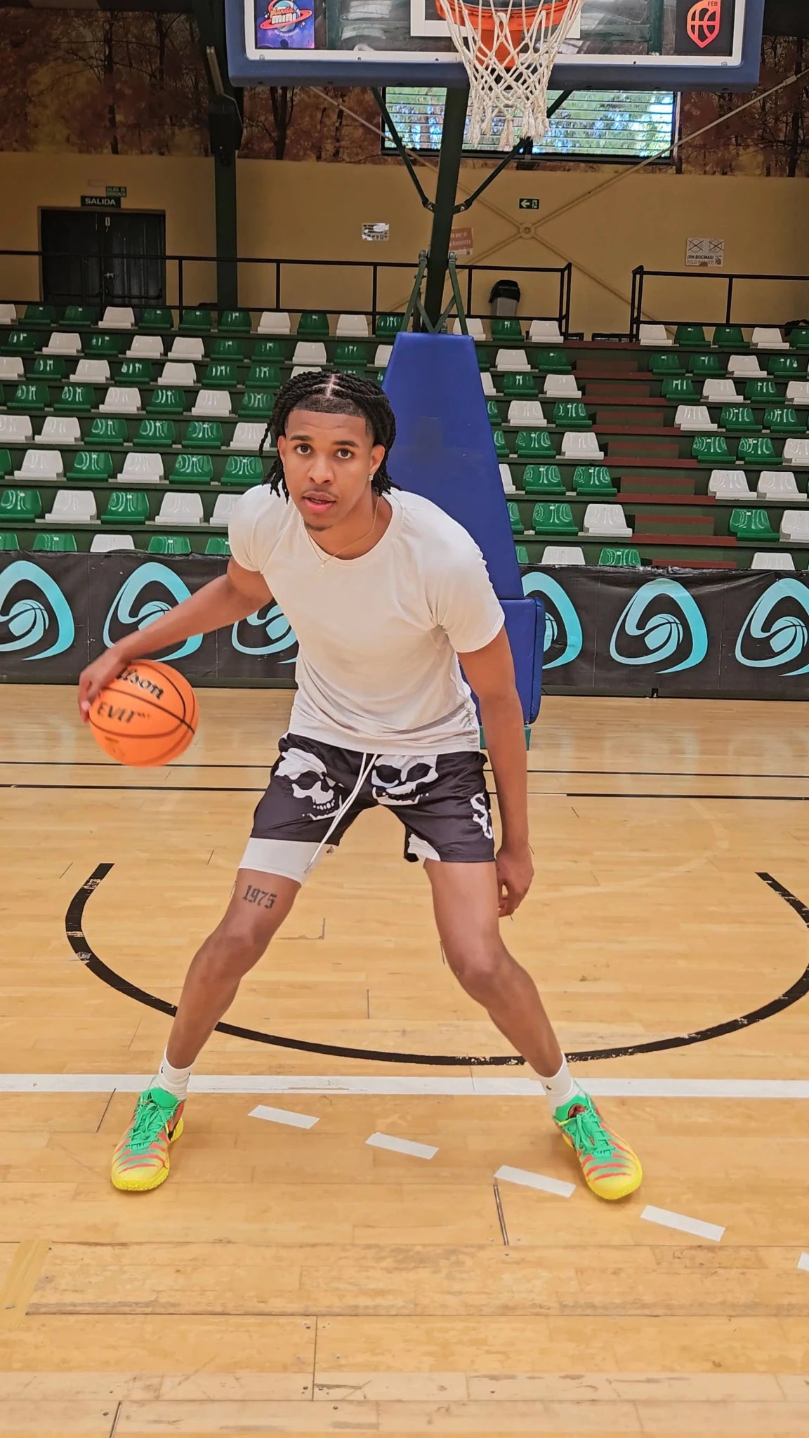 SwishGang player in dribbling stance wearing Skull basketball shorts on indoor hardwood court