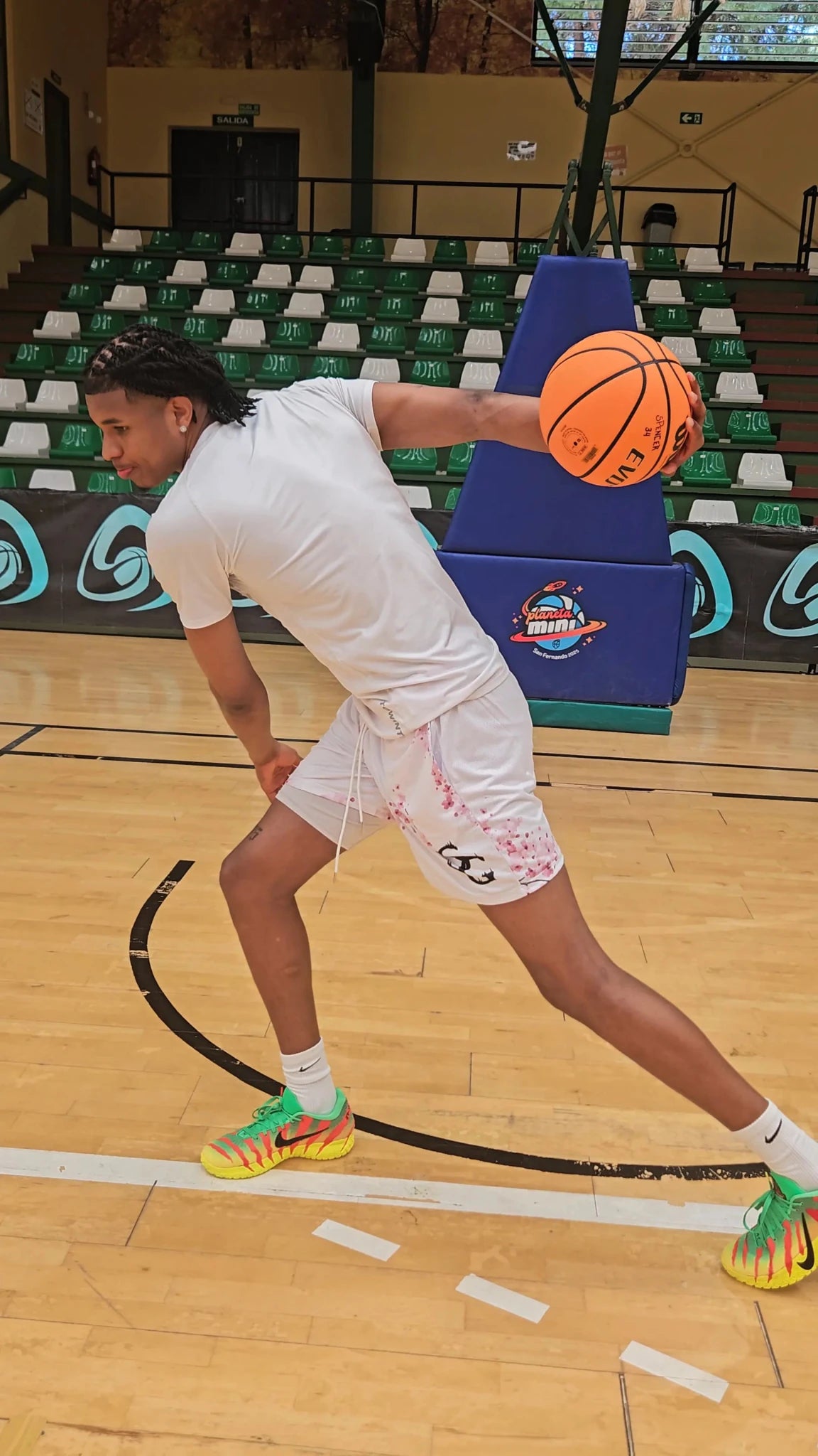 SwishGang player performing dribble move wearing Cherry Blossom white basketball shorts on indoor hardwood court