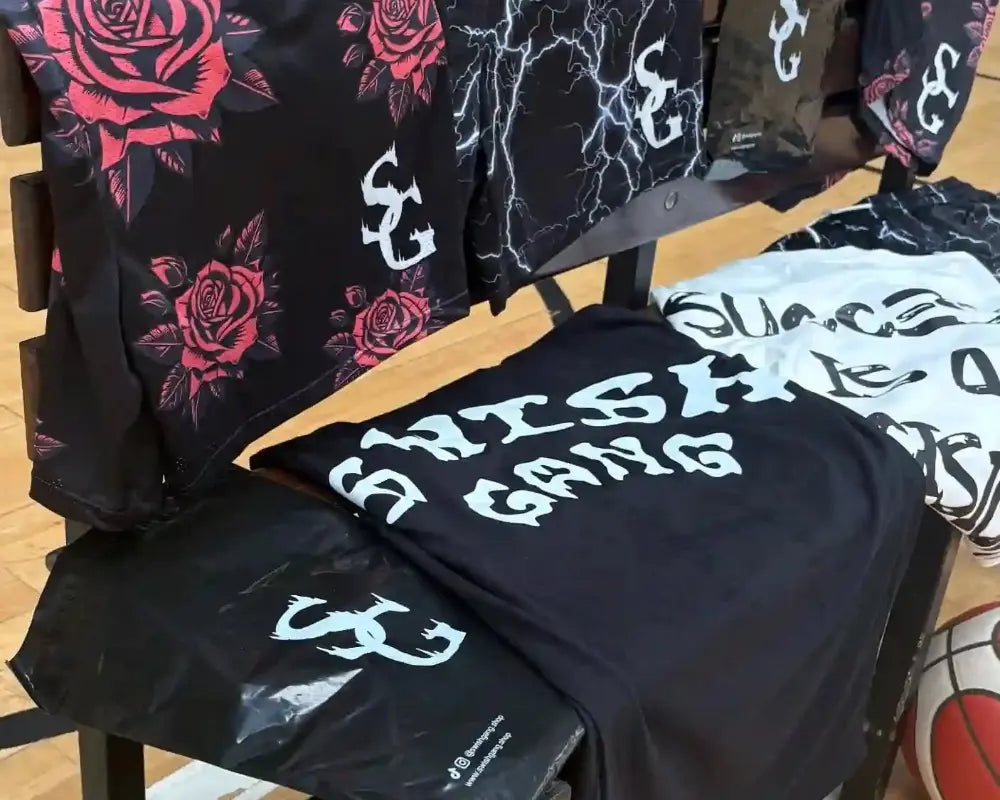 Display of roses shorts, thunder shorts, signature t-shirt and "success is a decision" t-shirt on a bench on a basketball court - SwishGang