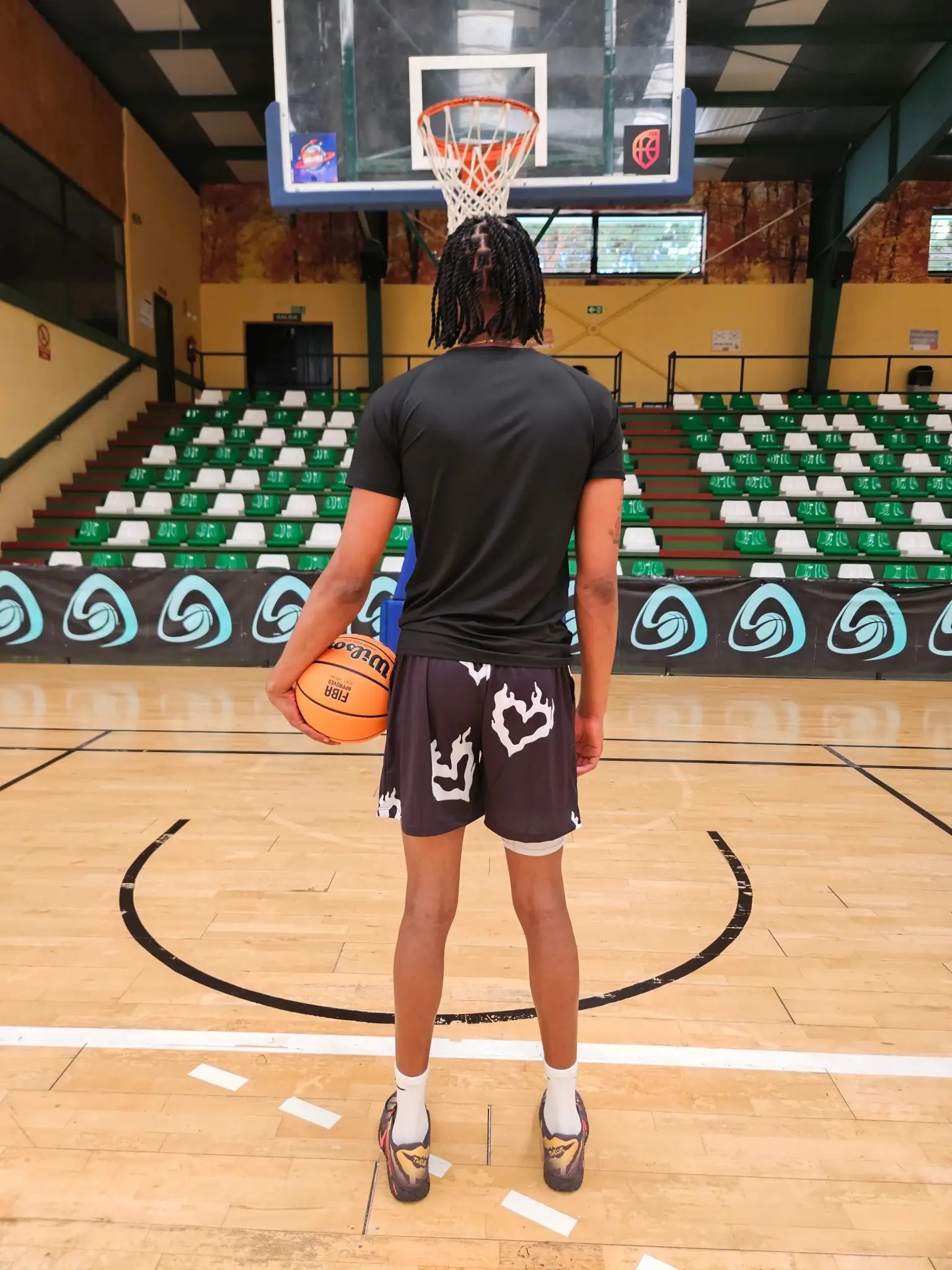 Back view of SwishGang model in black flaming heart basketball shorts on indoor court 
