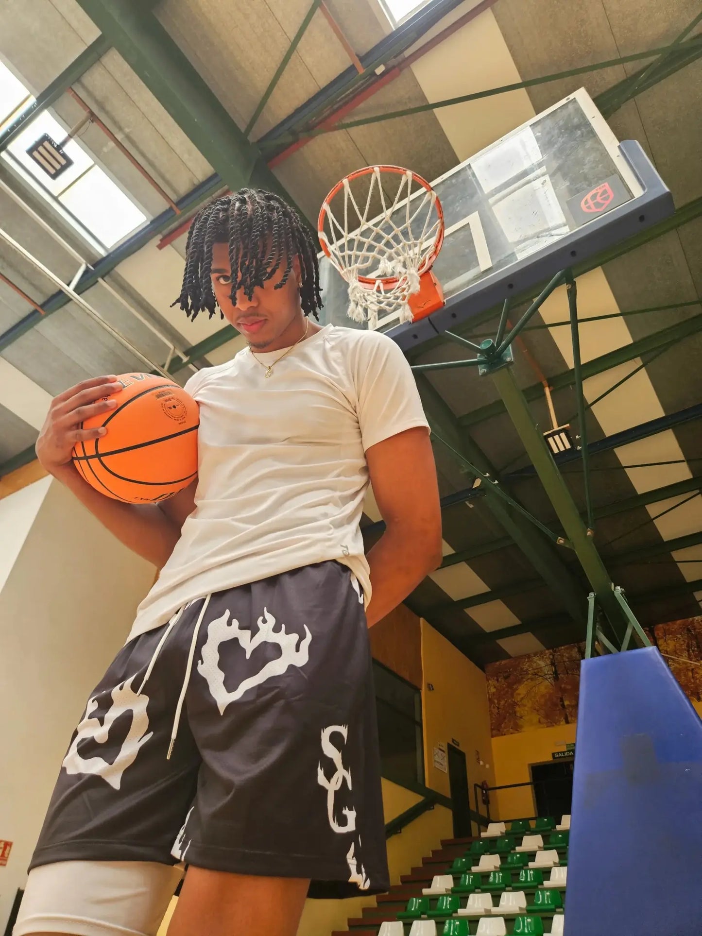 SwishGang Model wearing black basketball shorts with flaming heart print, holding basketball on court