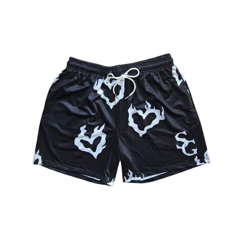 Studio product shot of black basketball shorts featuring a white flaming heart pattern and logo on the left leg