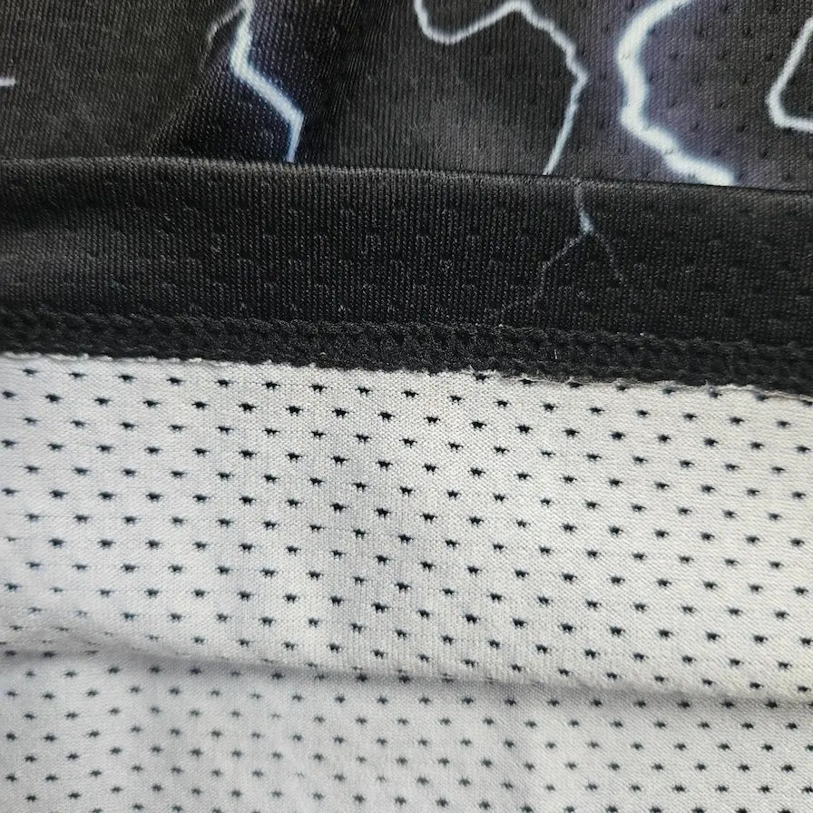 Single-layer mesh fabric detail showing lightning bolt print outer layer and breathable liner – SwishGang