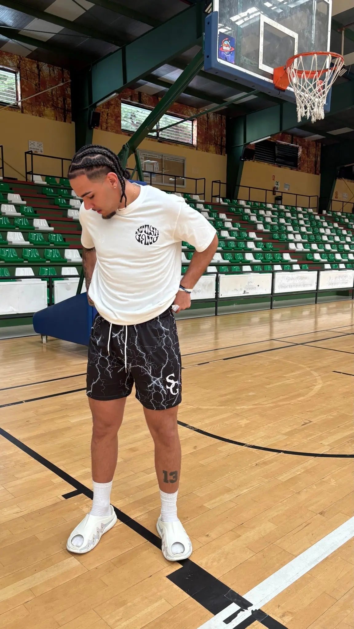 Basketball player wearing black basketball shorts with a white lightning bolt pattern, posing on an indoor court