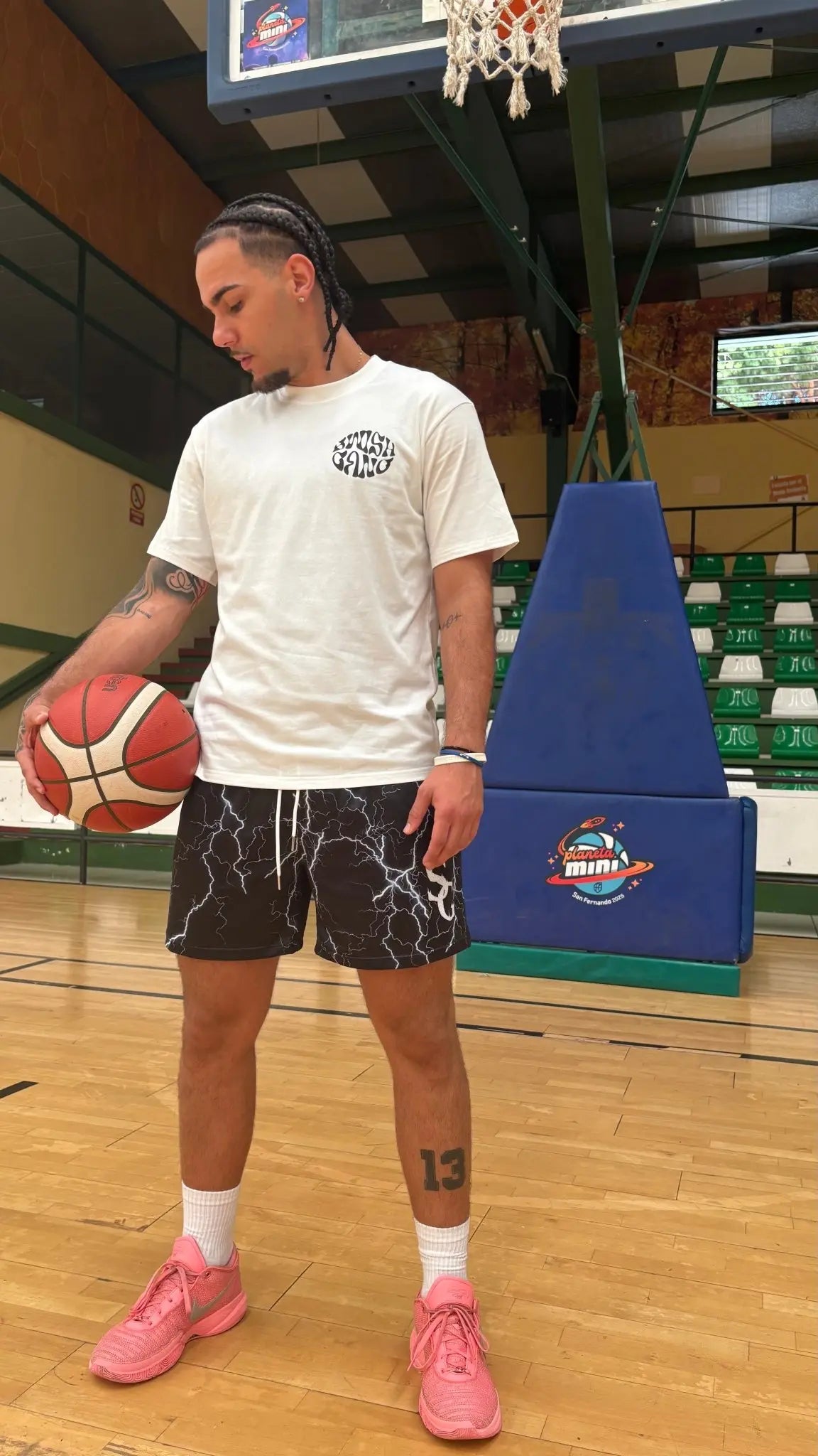 Basketball player wearing black basketball shorts with a white lightning bolt pattern, standing on an indoor basketball court