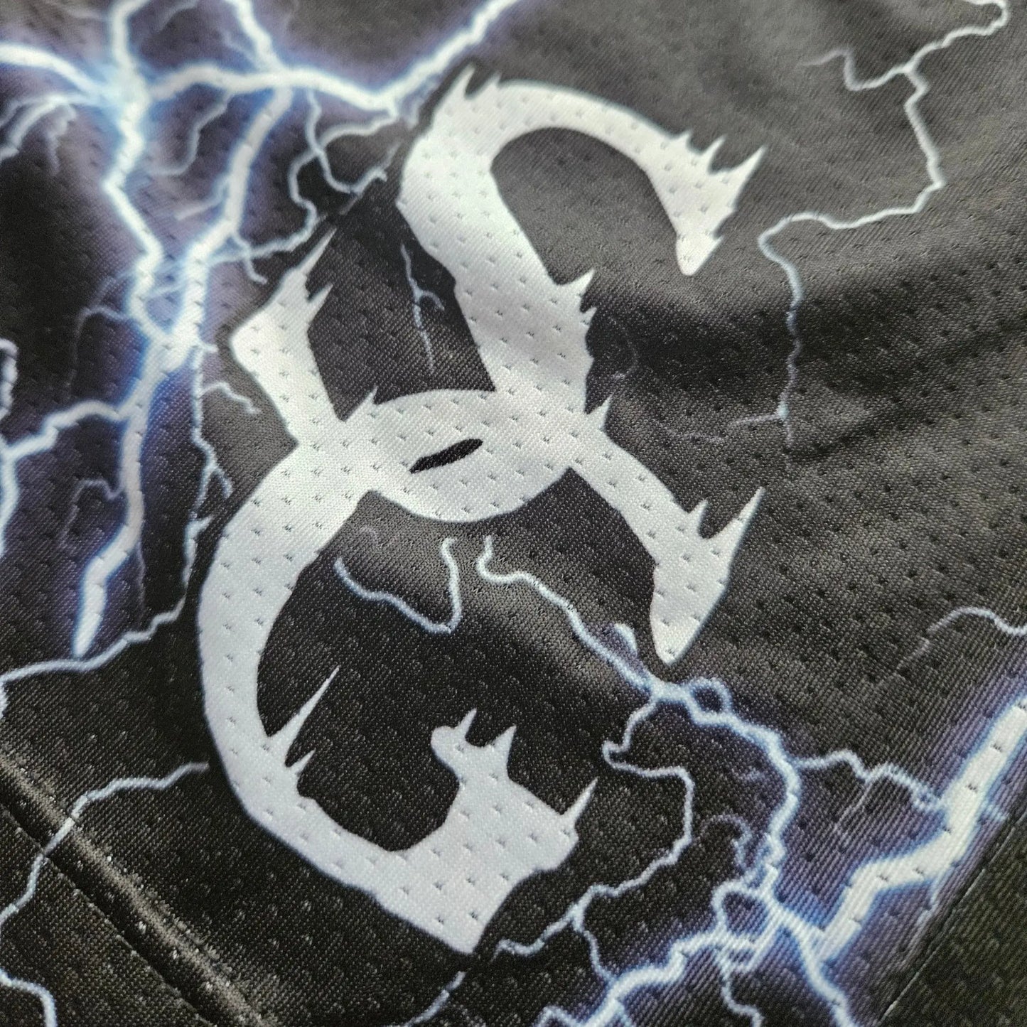 Close-up detail of the white logo printed on black basketball shorts with a lightning bolt pattern