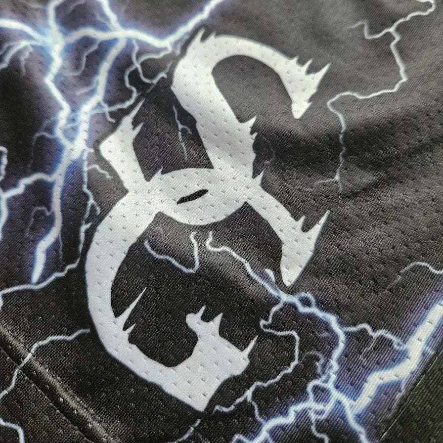 Close-up of SG logo detail on black lightning bolt print basketball shorts mesh fabric – SwishGang
