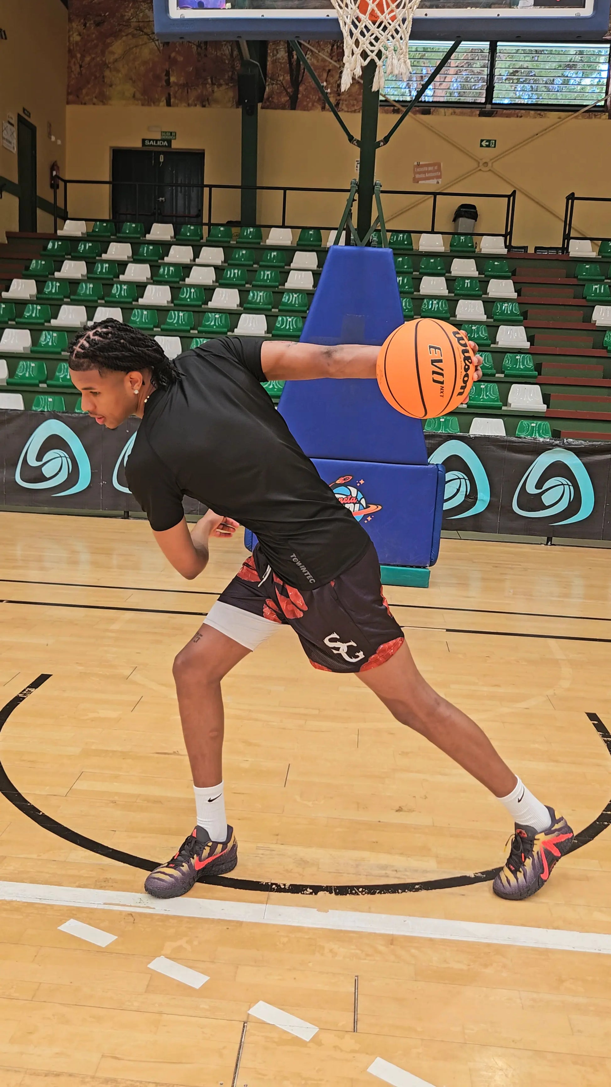 Action shot of a basketball player performing a move on the court while wearing black basketball shorts with a red lip/kiss print