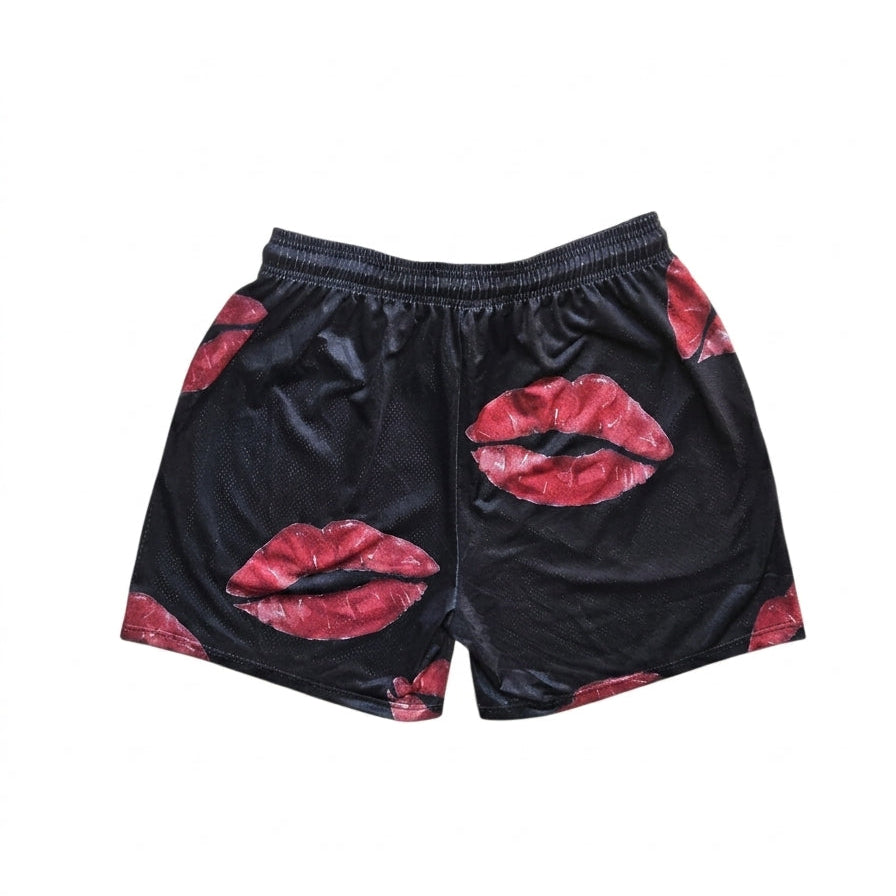 Studio product shot of the back of black basketball shorts featuring a red lip/kiss pattern