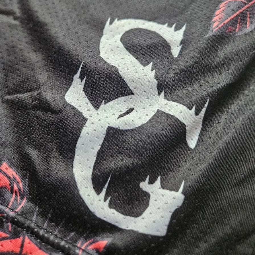 Close-up of SG logo detail on black red rose print basketball shorts mesh fabric – SwishGang