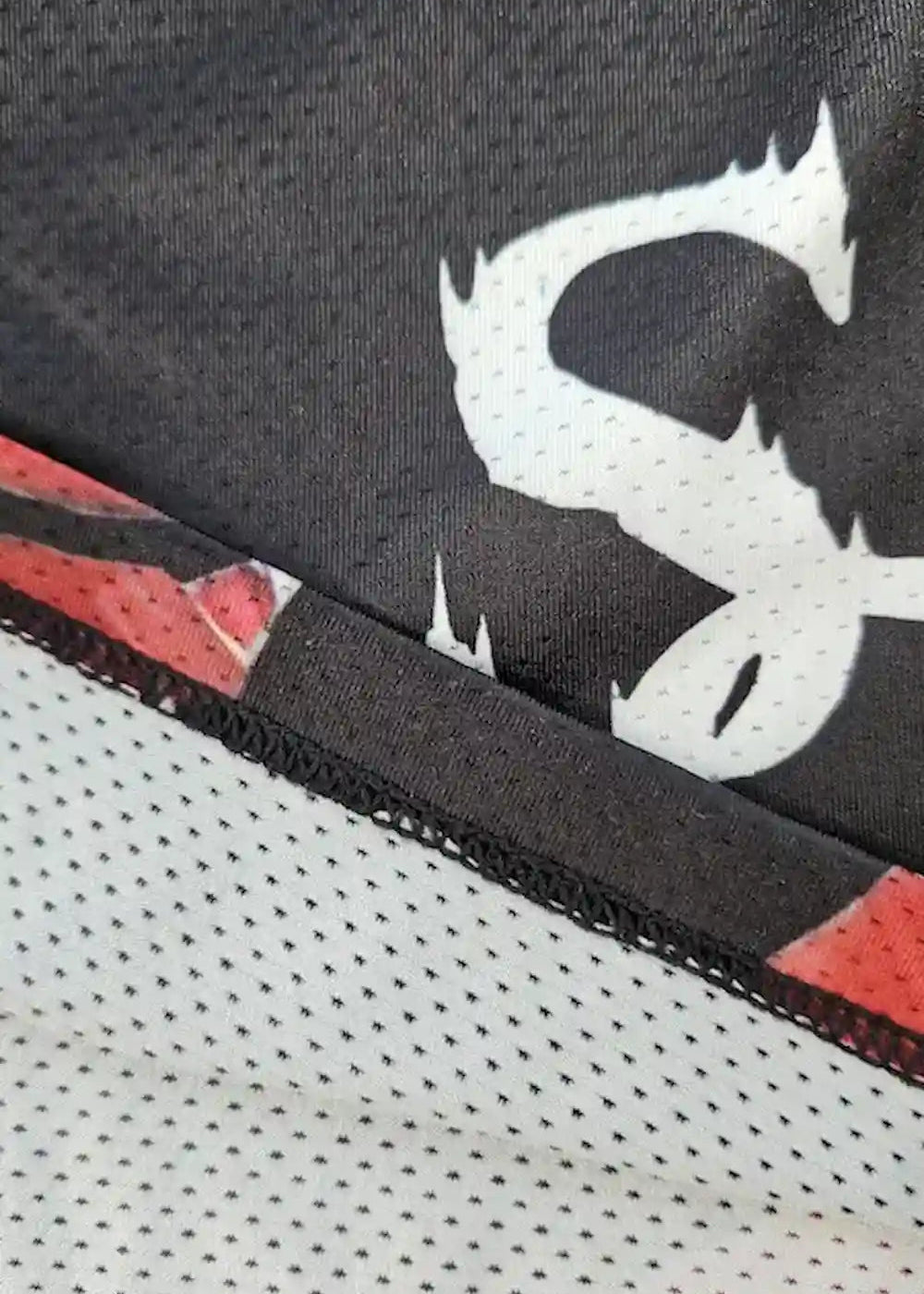 Close-up product shot of black basketball shorts with a red rose print and white mesh fabric featuring the SG logo and stitched hems.