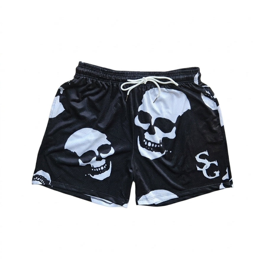 Studio product shot of black basketball shorts featuring a white skull pattern and logo on the left leg