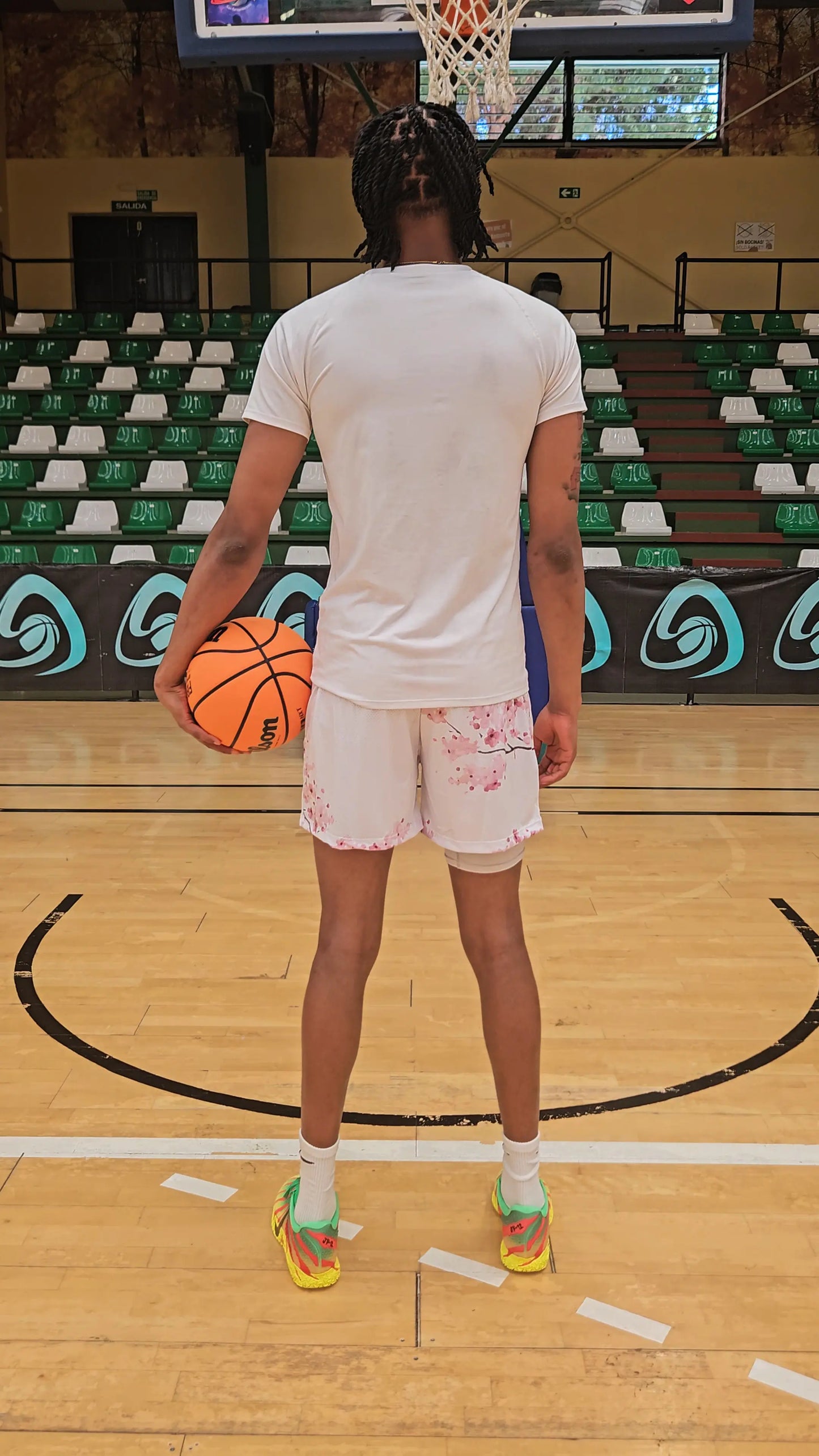 Back view of white basketball shorts with cherry blossom print, highlighting the athletic fit and design on a basketball court