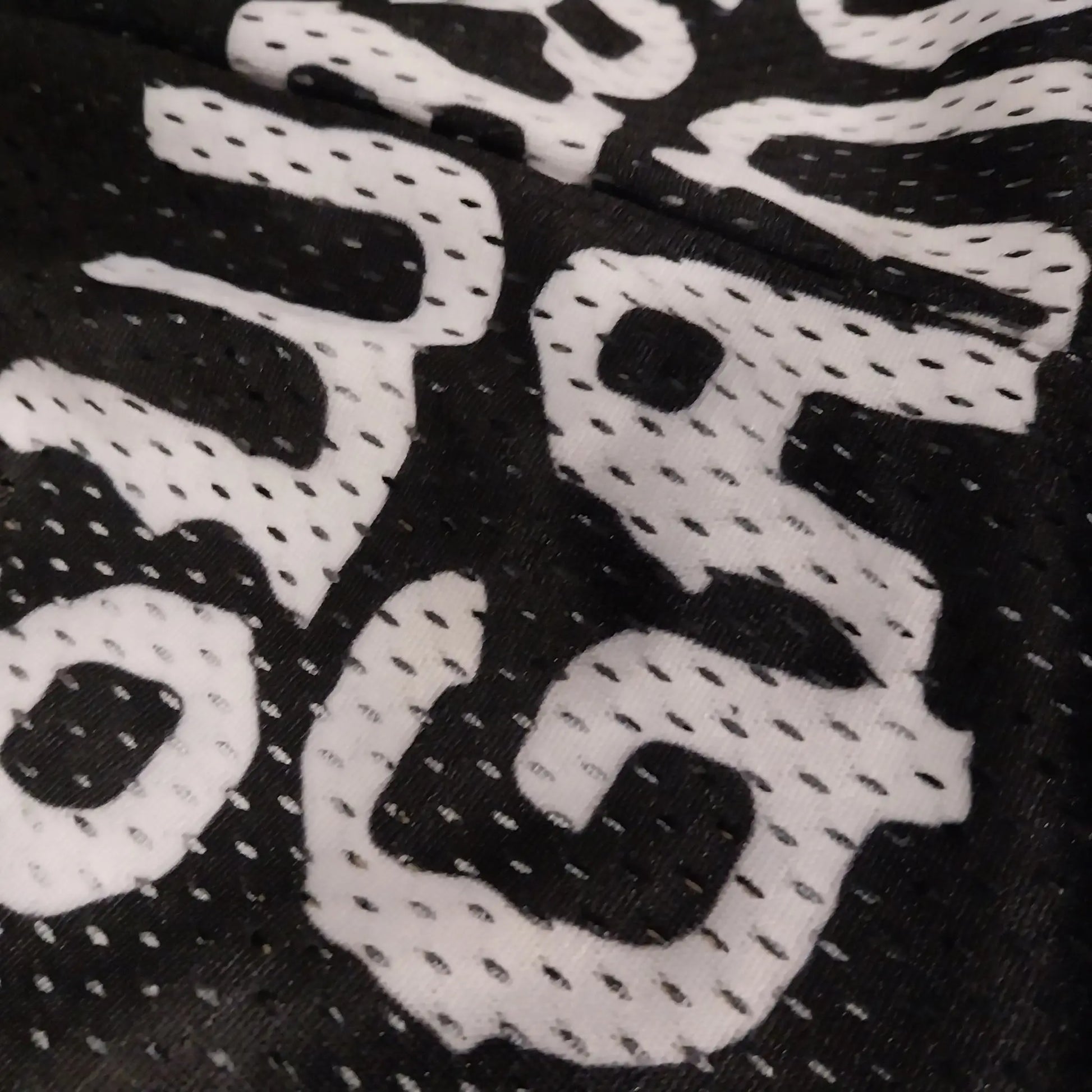 Close-up detail of the SwishGang logo printed on the mesh fabric of the black basketball shorts