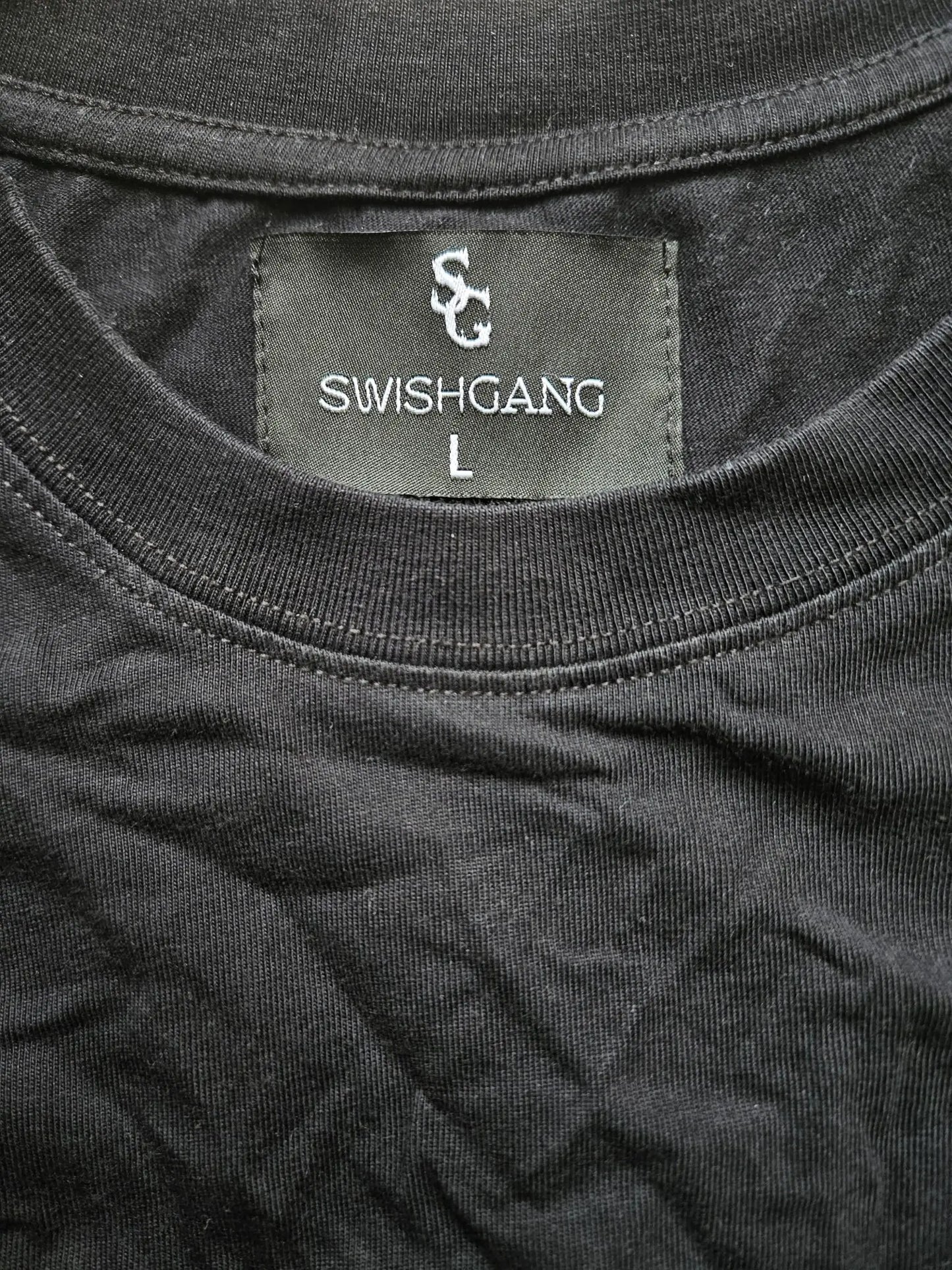 Close-up of the SwishGang neck label on a black t-shirt, indicating a size Large