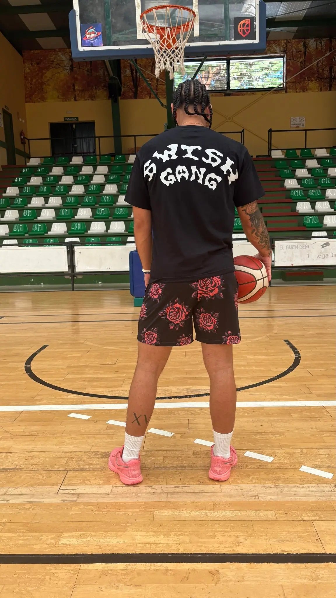 Back view of a basketball player wearing a black SwishGang t-shirt with the large, arched white logo on a basketball court
