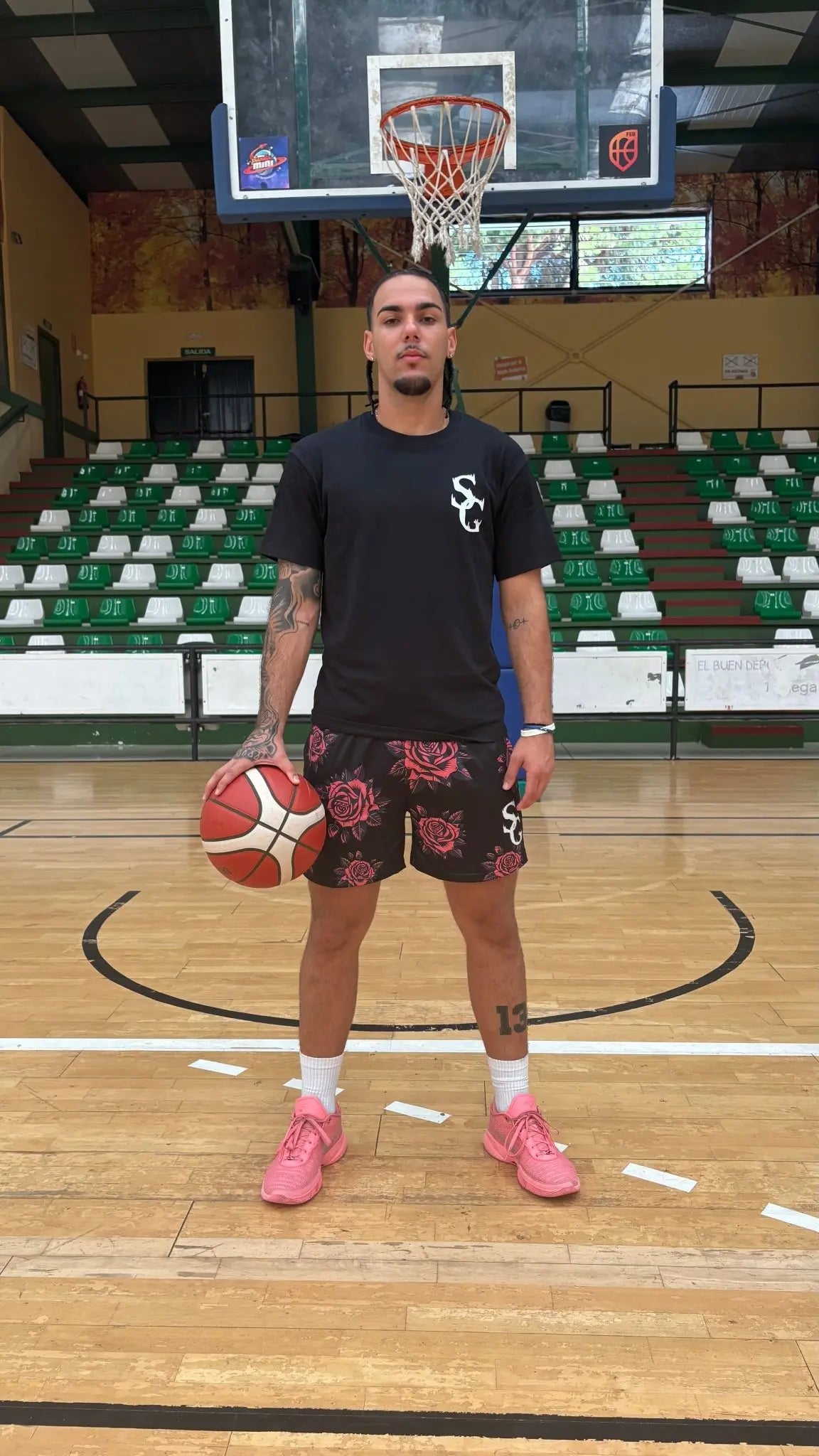 Full-length view of a basketball player wearing a black SwishGang t-shirt with a white chest logo on a basketball court