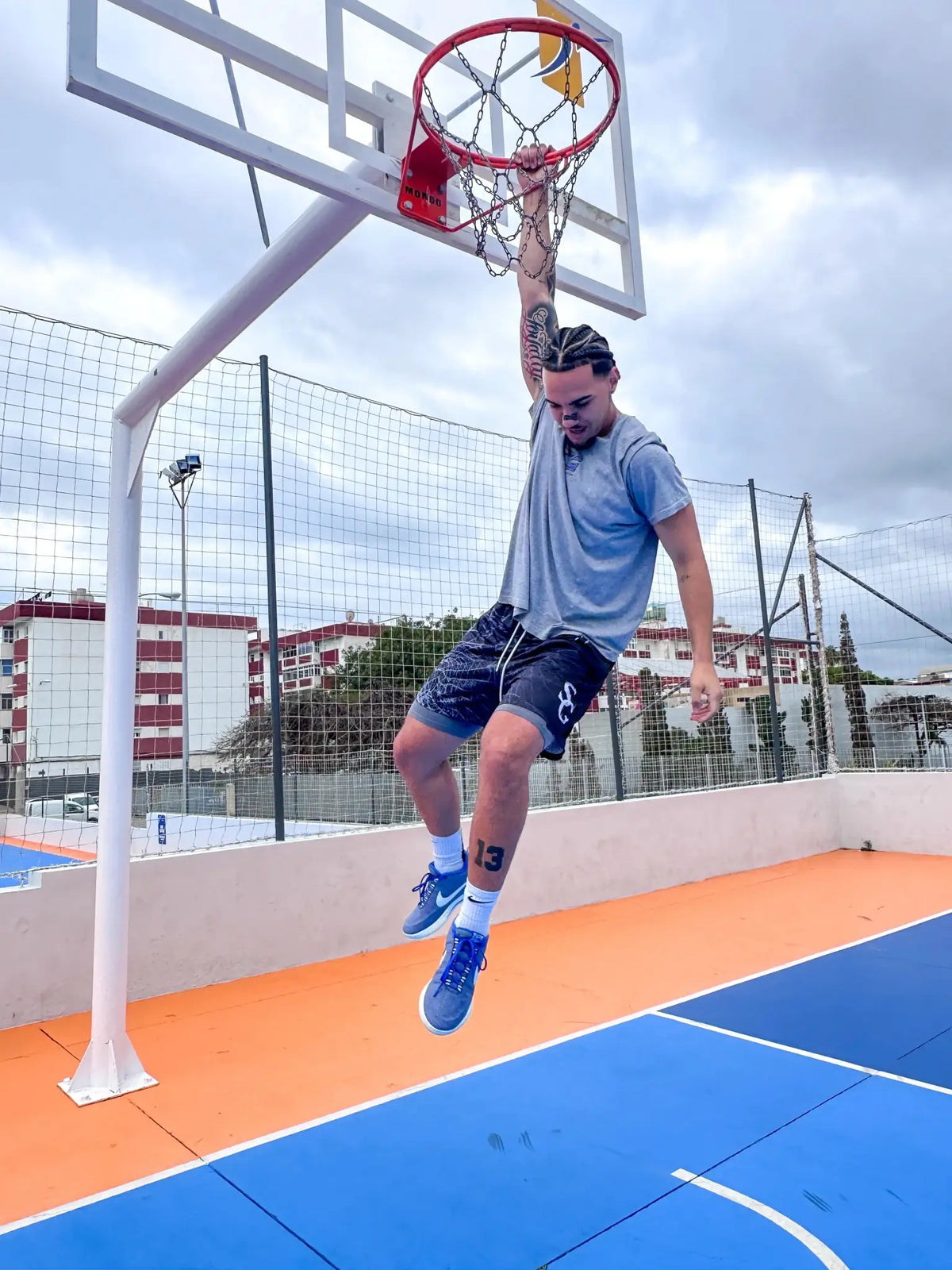 Player wearing black spider print basketball shorts dunking on outdoor court – SwishGang