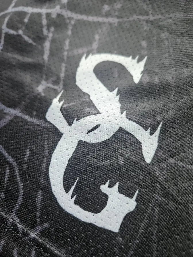 Close-up of SG logo detail on black spider web print basketball shorts mesh fabric 
