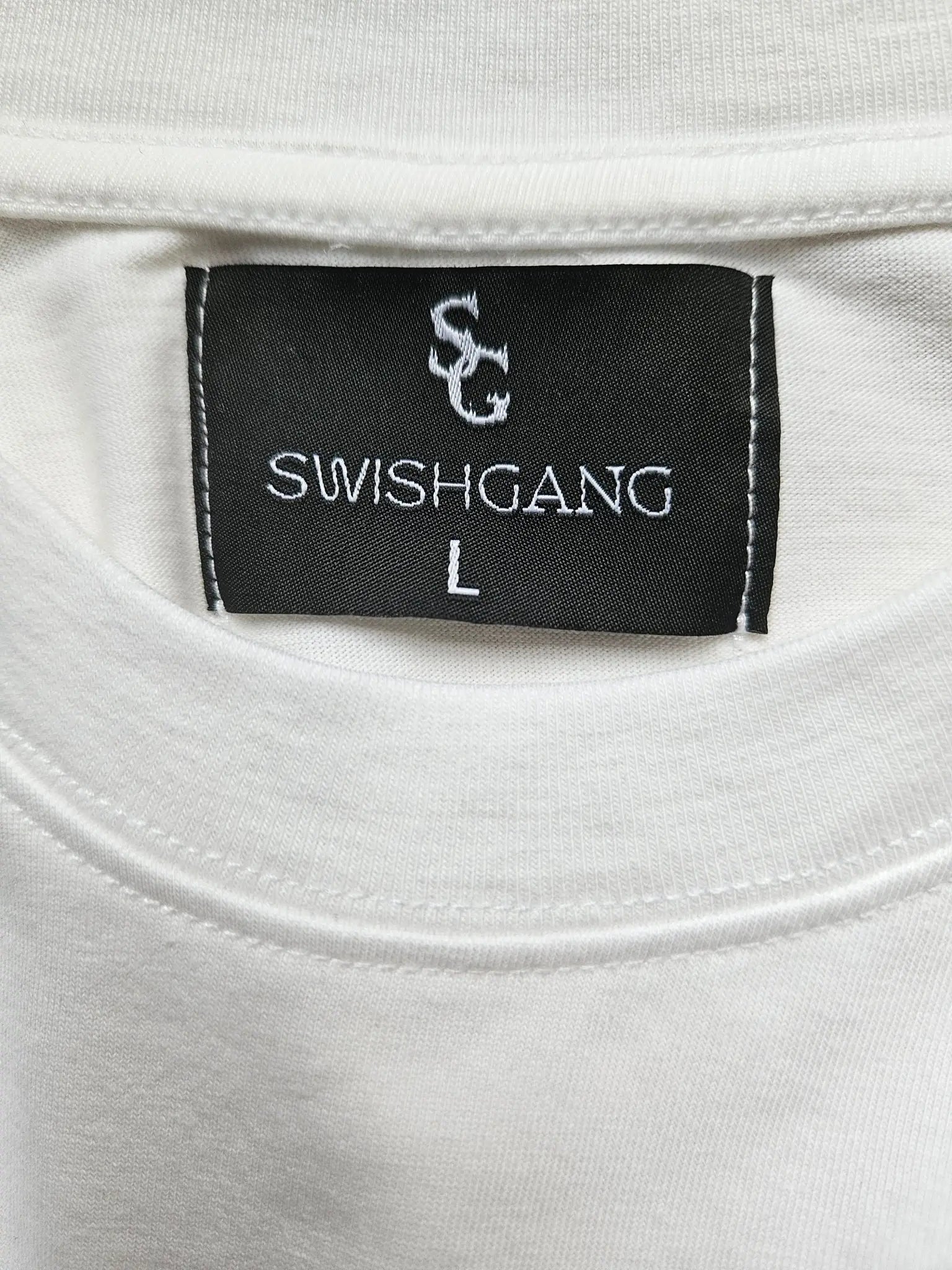 Close-up of the SwishGang neck label on a white t-shirt, indicating a size Large