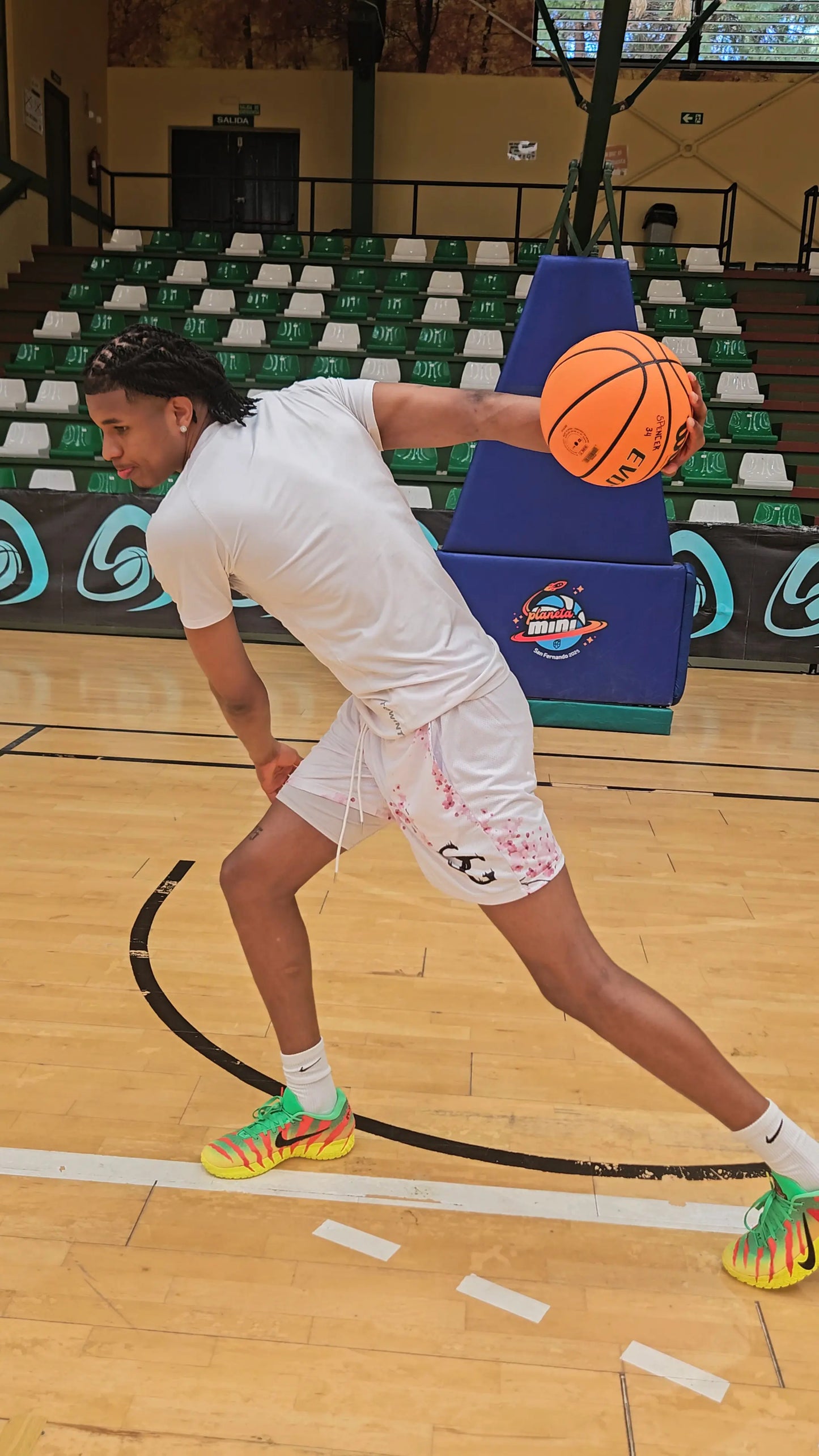 Action shot of a player performing a basketball move while wearing white cherry blossom print shorts on a court