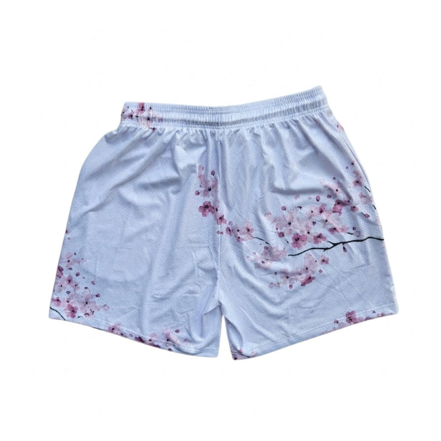 Studio product shot of the back of white basketball shorts featuring a pink cherry blossom branch print